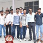 Eight young men pose together outside a school building, with the Heritage International School Aligarh logo visible in the lower left.